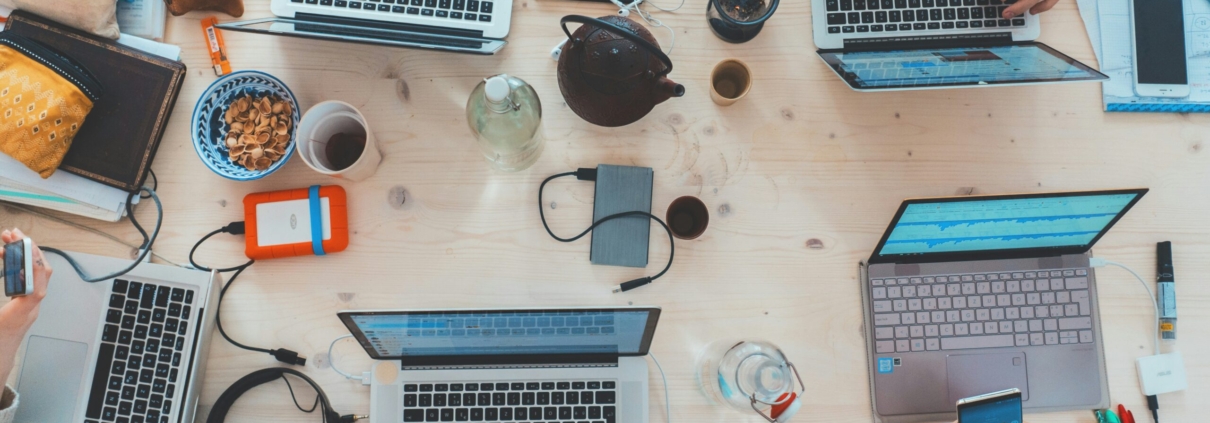 people sitting down near table with assorted laptop computers