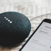 Turned-on charcoal Google Home Mini and smartphone photo