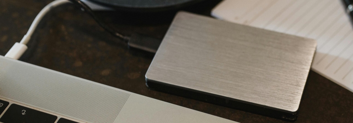 Free Closeup of an external hard drive connected to a laptop with a USB cable on a desk. Stock Photo