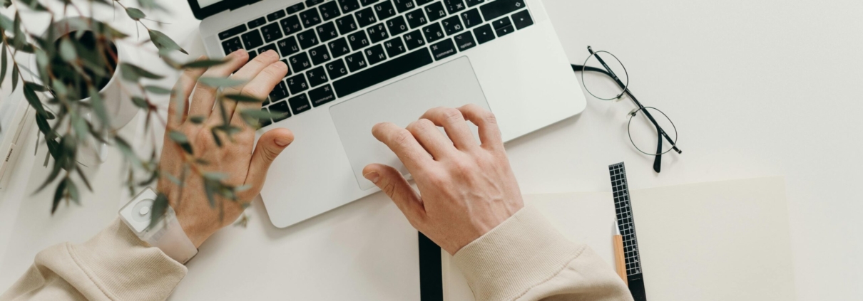 Free An overhead view of a person working on a laptop in a minimalist home office setting. Stock Photo