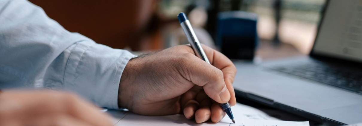 Free A person calculating finances with a calculator and pen on a desk indoors. Stock Photo